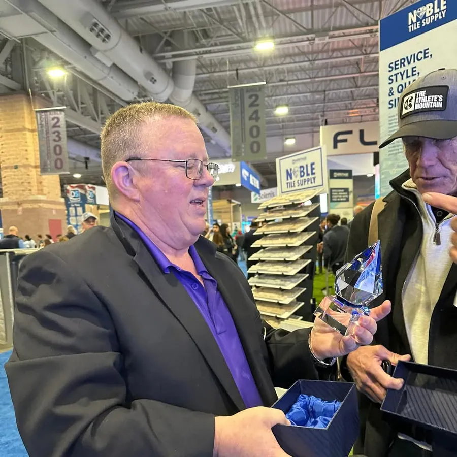 Rob Stewart holding a crystal award on a pool and spa trade show floor